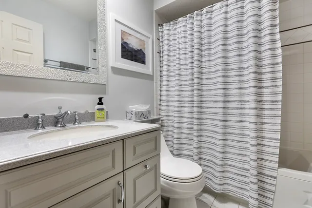 a bathroom with a granite countertop toilet sink and mirror