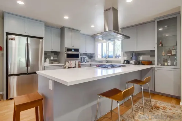 a kitchen with stainless steel appliances a sink a stove a refrigerator cabinets and a dining table