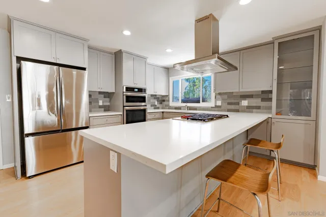 a kitchen with stainless steel appliances a refrigerator a sink a stove a dining table and chairs