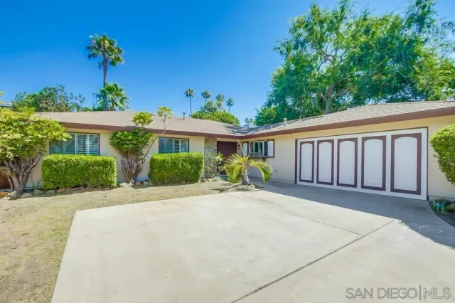 a front view of a house with a yard and potted plants