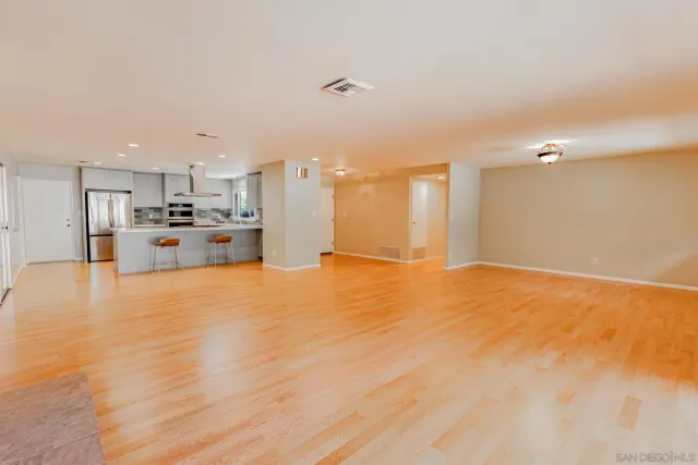 a view of a kitchen with kitchen island a sink wooden floor and stainless steel appliances