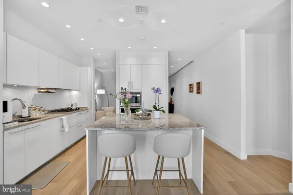 a kitchen with stainless steel appliances granite countertop a sink a stove a refrigerator and a dining table with wooden floor