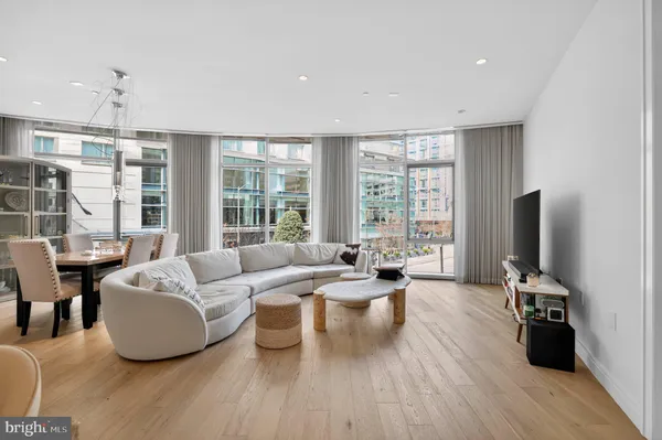 a living room with furniture large windows and wooden floor