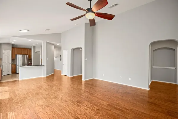 a view of an empty room with window and wooden floor