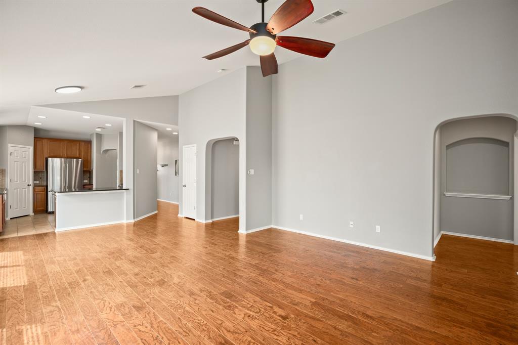 a view of an empty room with window and wooden floor