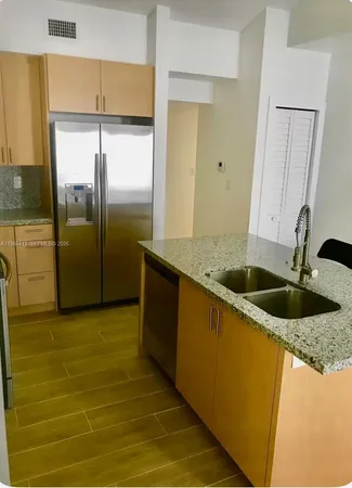 a kitchen with stainless steel appliances granite countertop a sink and a refrigerator
