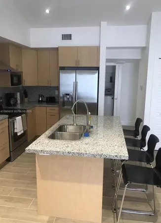 a kitchen with stainless steel appliances granite countertop a sink a stove and a wooden cabinets