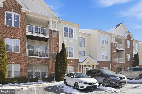 a front view of a residential apartment building with cars parked