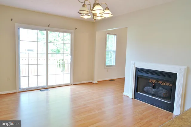 an empty room with wooden floor fireplace and windows