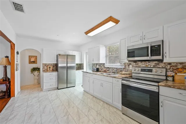 a kitchen with stainless steel appliances granite countertop a stove top oven a sink dishwasher a refrigerator and a microwave oven with wooden floor