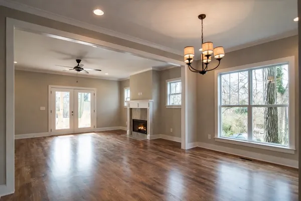 a view of a room with wooden floor chandelier and windows