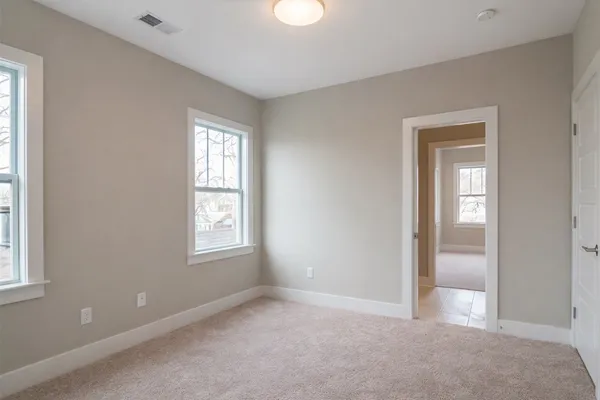 a view of an empty room with window and closet area
