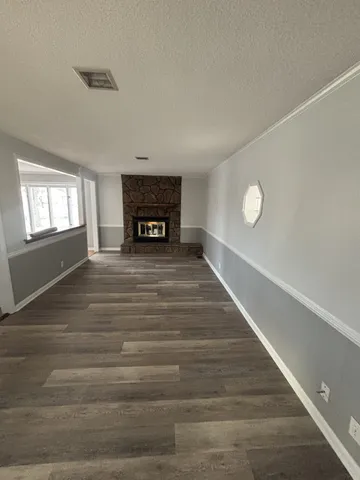 a view of an empty room with window and wooden floor