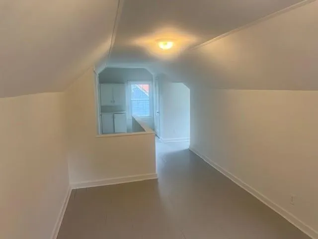 a view of hallway with window and wooden floor