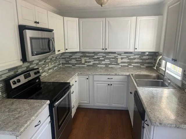 a kitchen with granite countertop a sink stove and cabinets