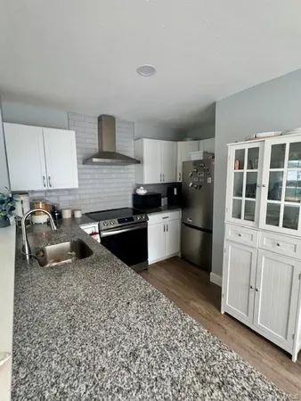 a kitchen with granite countertop a stove sink and cabinets