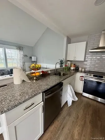 a kitchen with granite countertop a sink a counter space appliances and cabinets