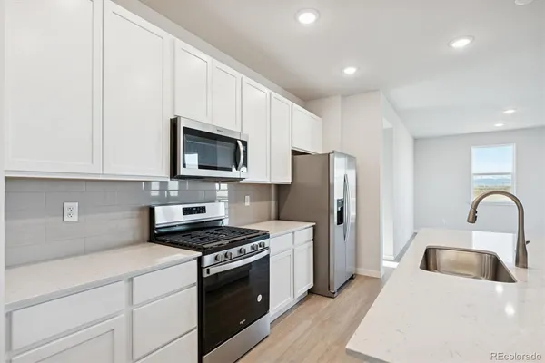a kitchen with granite countertop a refrigerator stove and microwave