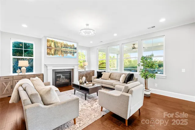 a view of a kitchen counter top space with sink a center island stainless steel appliances wooden floor and living room view