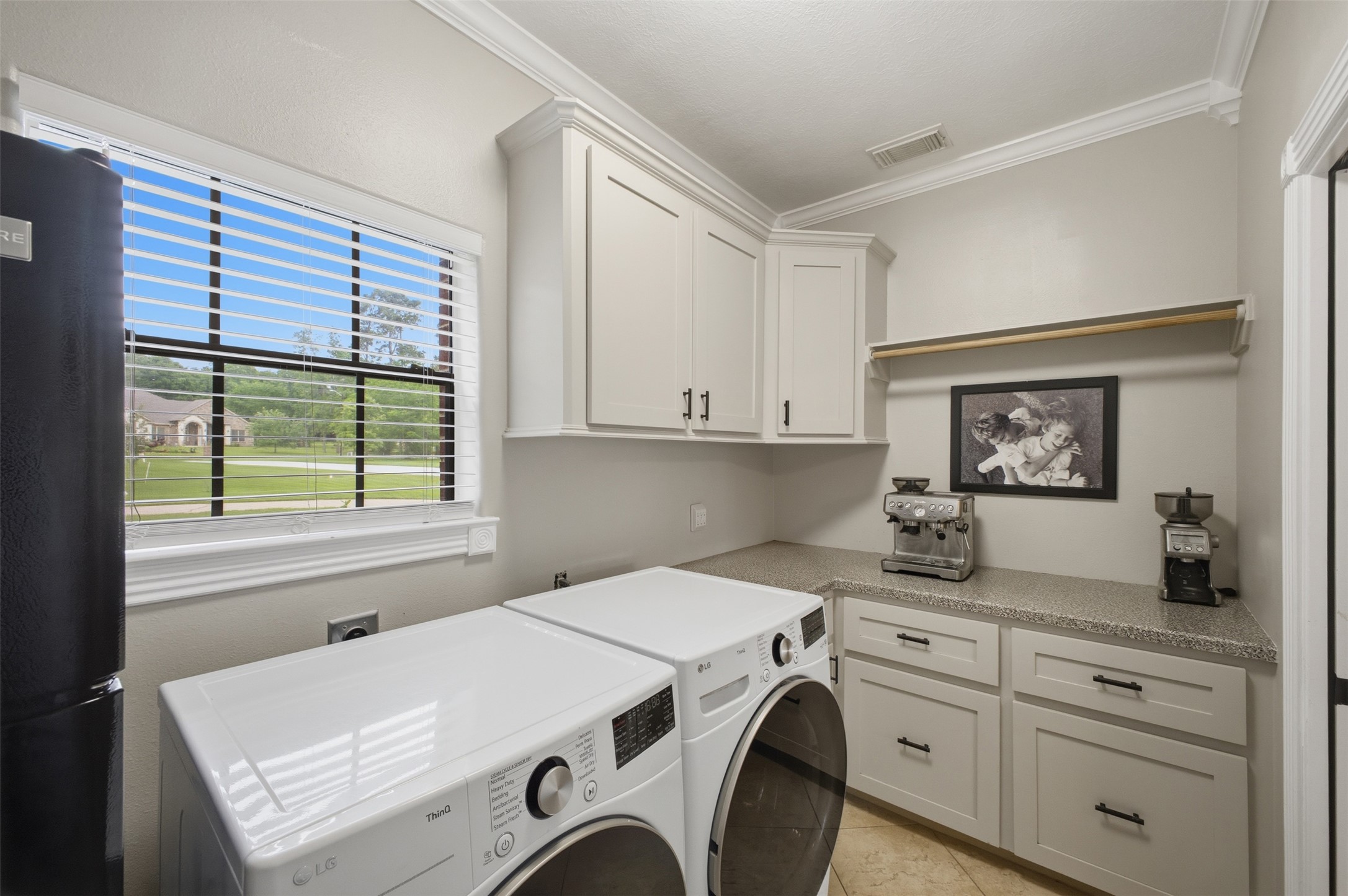 12710 Aries Loop Willis, TX 77318 - Photo 17 of 40 This utility area features white cabinetry with dark hardware, a window offering views of greenery, and crown molding