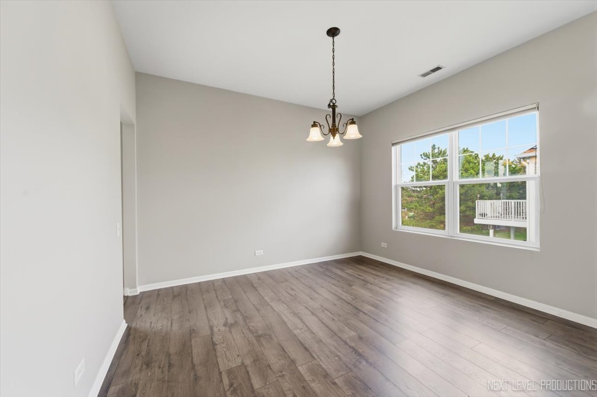 1102 Delta Drive, Unit 1102 Elgin, IL 60123 - Photo 11 of 29 an empty room with wooden floor chandelier and windows