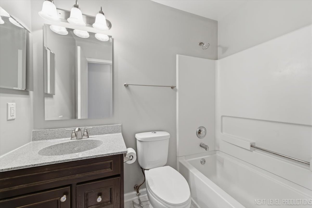 1102 Delta Drive, Unit 1102 Elgin, IL 60123 - Photo 26 of 29 a bathroom with a granite countertop sink a toilet and bathtub