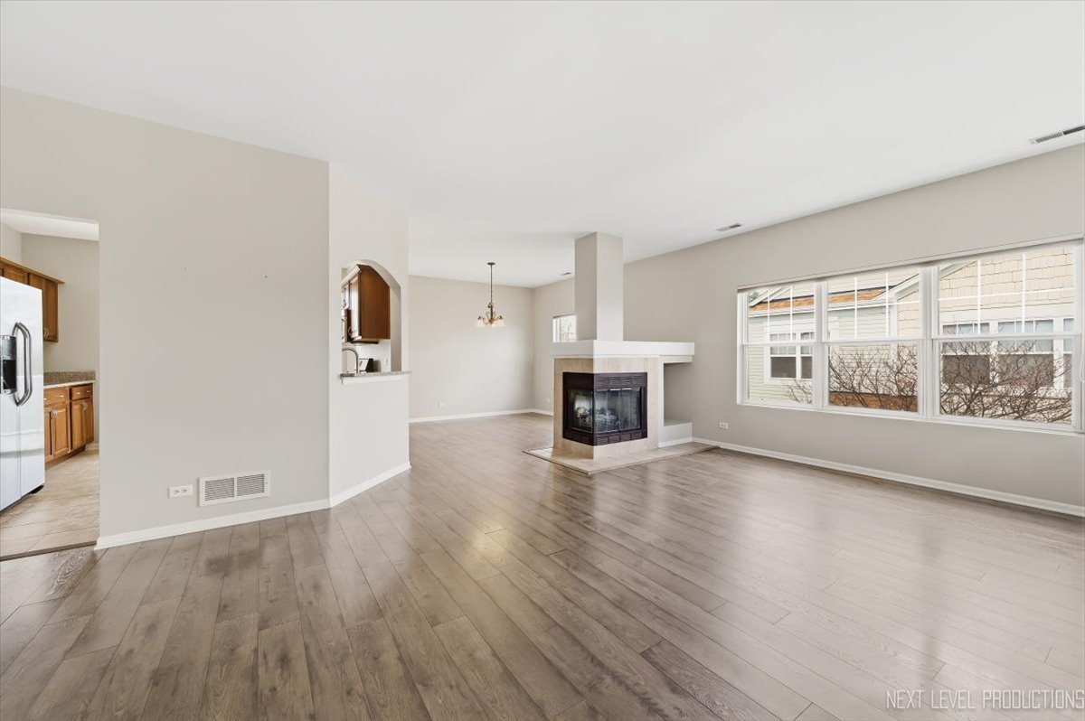 1102 Delta Drive, Unit 1102 Elgin, IL 60123 - Photo 6 of 29 an empty room with wooden floor fireplace and windows