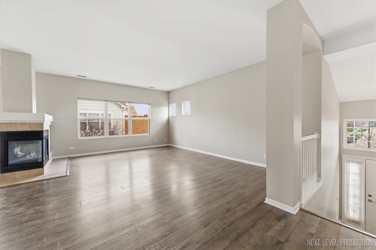 1102 Delta Drive, Unit 1102 Elgin, IL 60123 - Photo 9 of 29 an empty room with wooden floor fireplace and windows