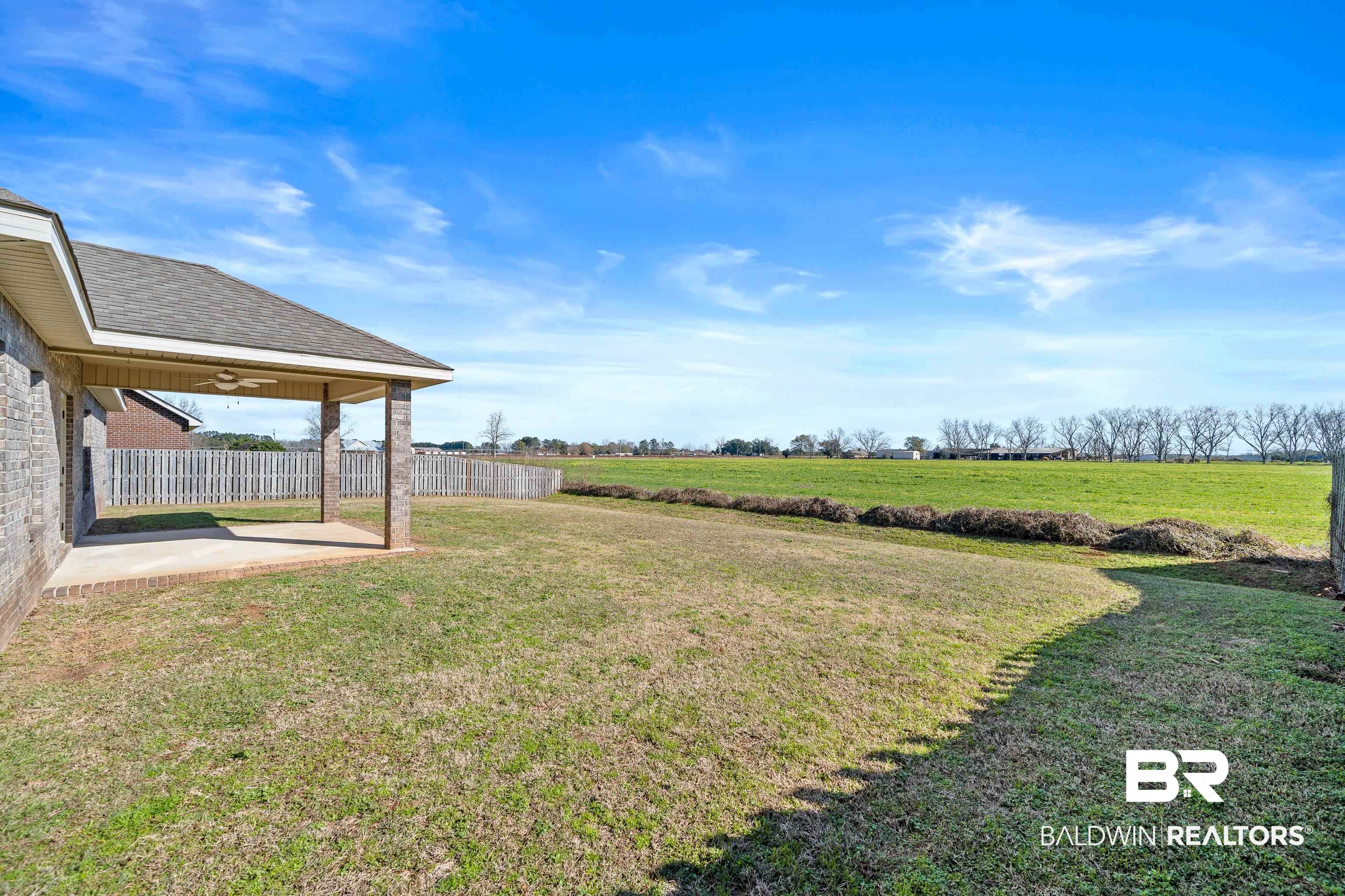25350 Spindle Lane Daphne, AL 36526 - Photo 31 of 32 View of yard featuring ceiling fan, a rural view, and a patio