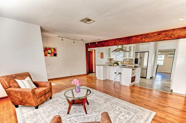 a living room with furniture kitchen view and a wooden floor