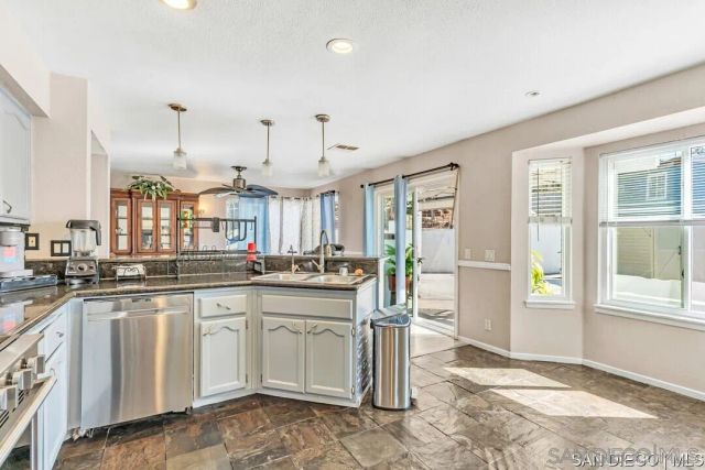 a large white kitchen with granite countertop a sink and cabinets