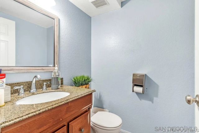 a bathroom with a granite countertop sink mirror vanity and toilet