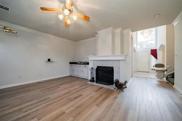 a view of an empty room with wooden floor fireplace and a window