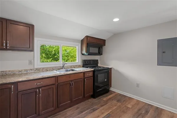 a kitchen with granite countertop a stove a sink and a microwave