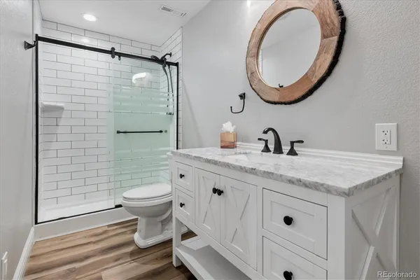 a bathroom with a granite countertop toilet a sink and a mirror