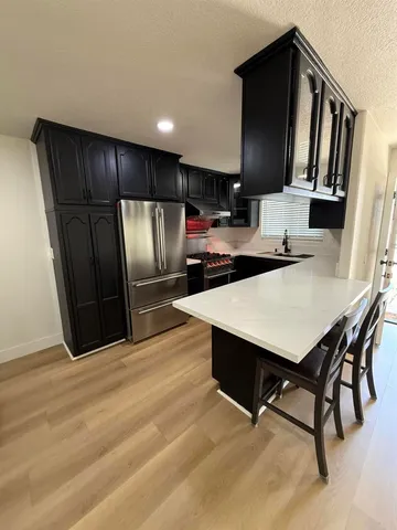 a kitchen with stainless steel appliances kitchen island granite countertop a refrigerator a stove a sink with a dining table and chair