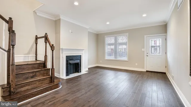 a view of an empty room with wooden floor fireplace and a window