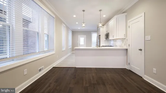 a view of a kitchen with kitchen island a sink wooden floor and a large window