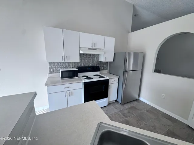 a kitchen with a refrigerator sink and cabinets