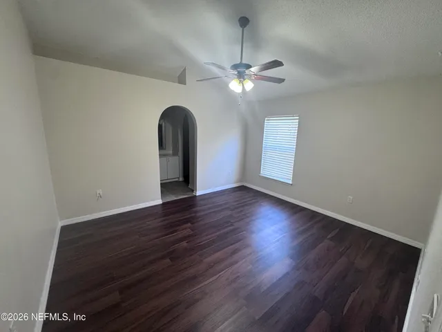a view of an empty room with a window and wooden floor