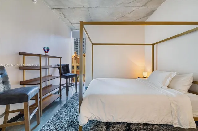 a bedroom with a bed a dresser with wooden floor