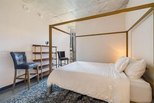 a bedroom with a bed a chair and a potted plant