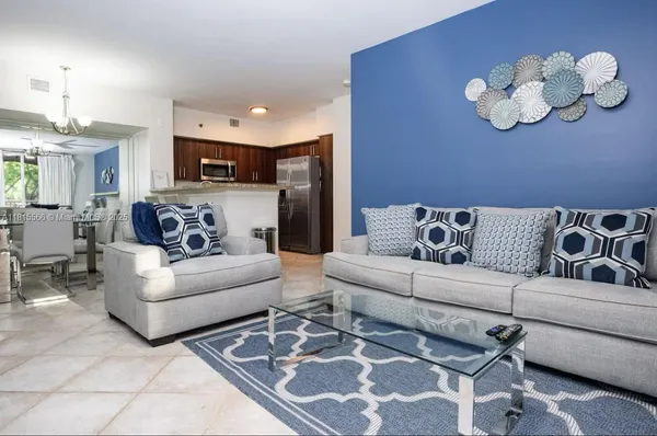 a living room with furniture kitchen view and a chandelier