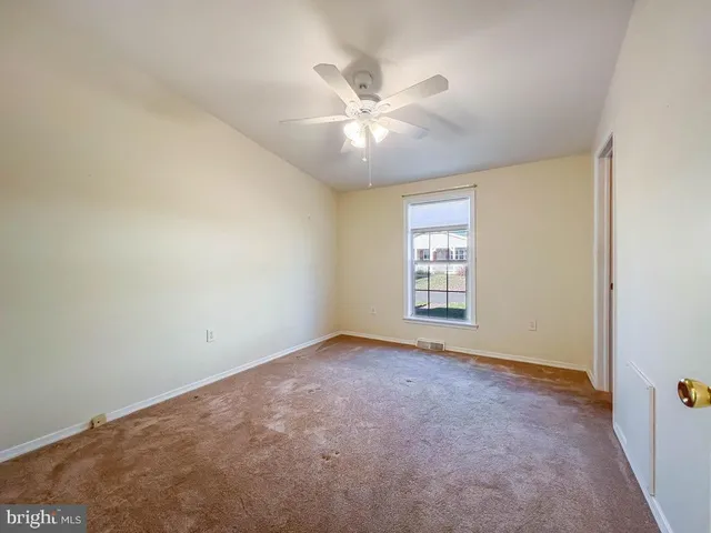 an empty room with a ceiling fan and a window
