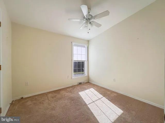 an empty room with a chandelier fan and windows