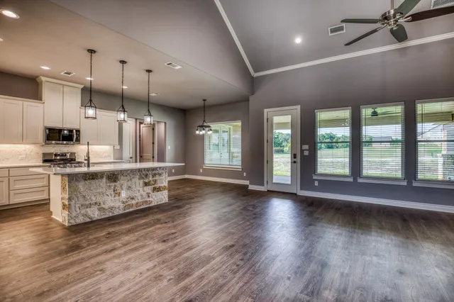 a large kitchen with stainless steel appliances kitchen island a large counter top and wooden floors
