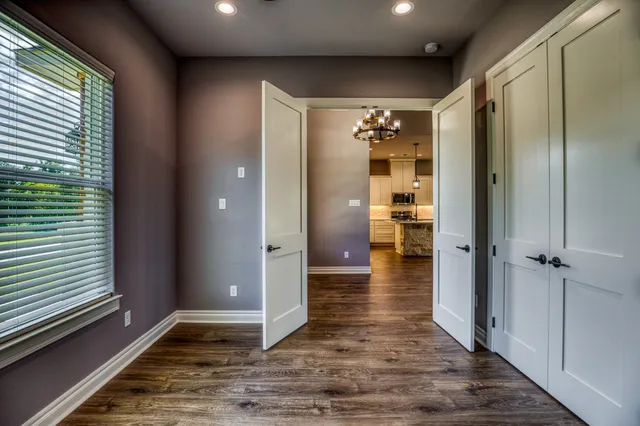 a view of a hallway with wooden floor and a bathroom