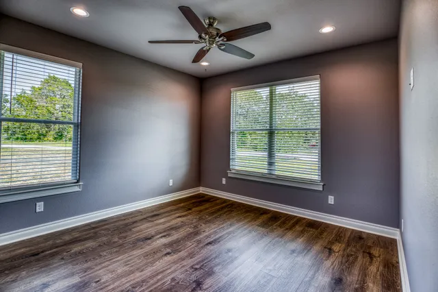 a view of an empty room with a window and wooden floor