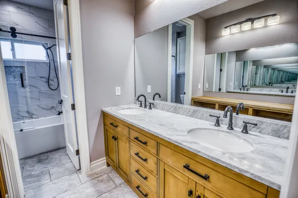 a bathroom with a granite countertop double vanity sink a mirror and a bathtub