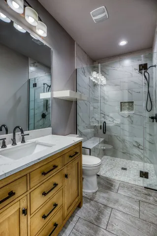 a bathroom with a granite countertop sink toilet and shower